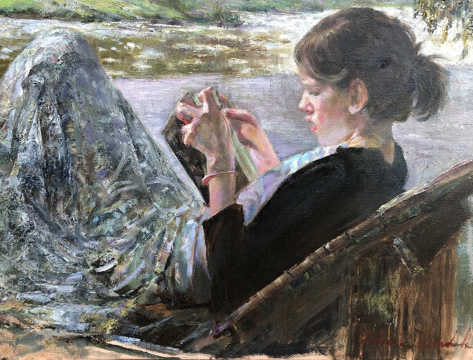 Girl reading beside stream